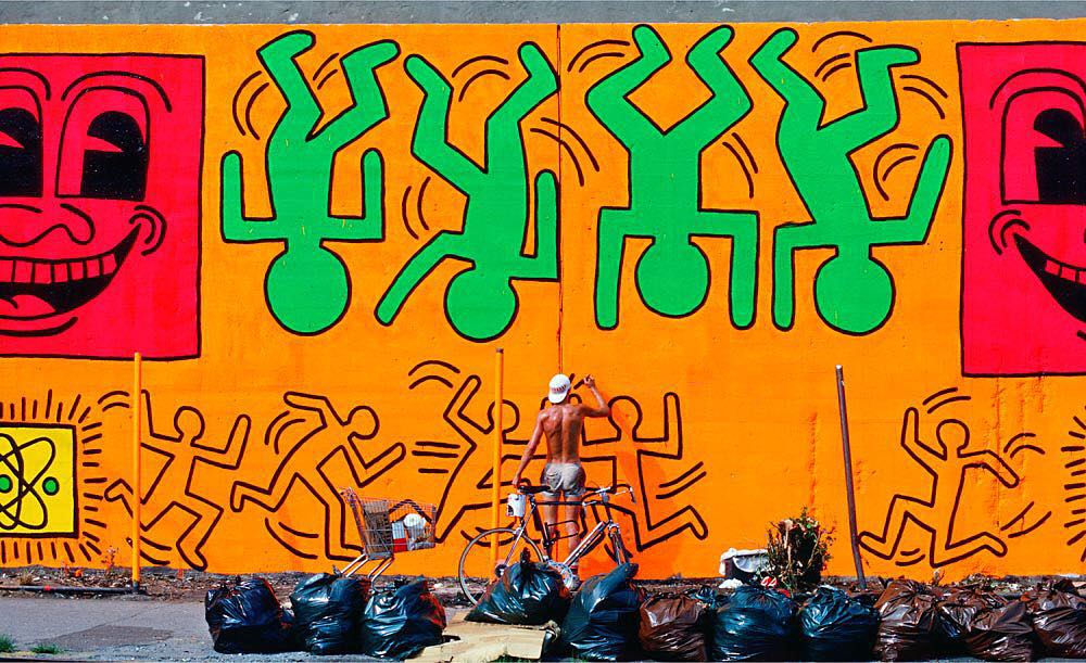 This image has an empty alt attribute; its file name is Martha_cooper_Keith-Haring-painting-the-HoustonBowery-wall-in-1982_art_plugged.jpg Keith Haring painting the Houston/Bowery wall in 1982  Photo Courtesy of ©Martha Cooper